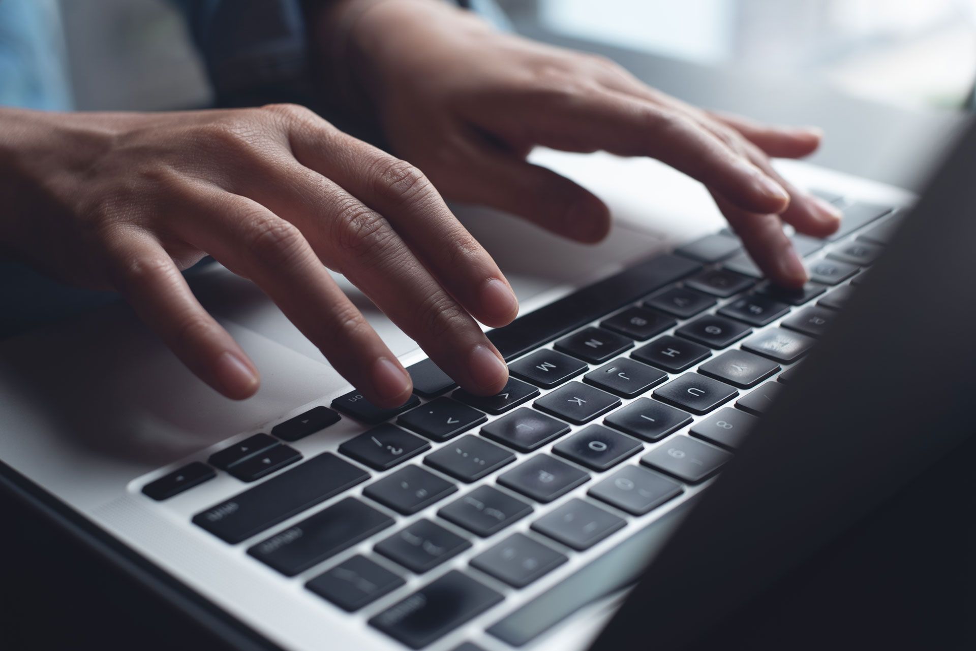 Hands typing on a laptop keyboard.