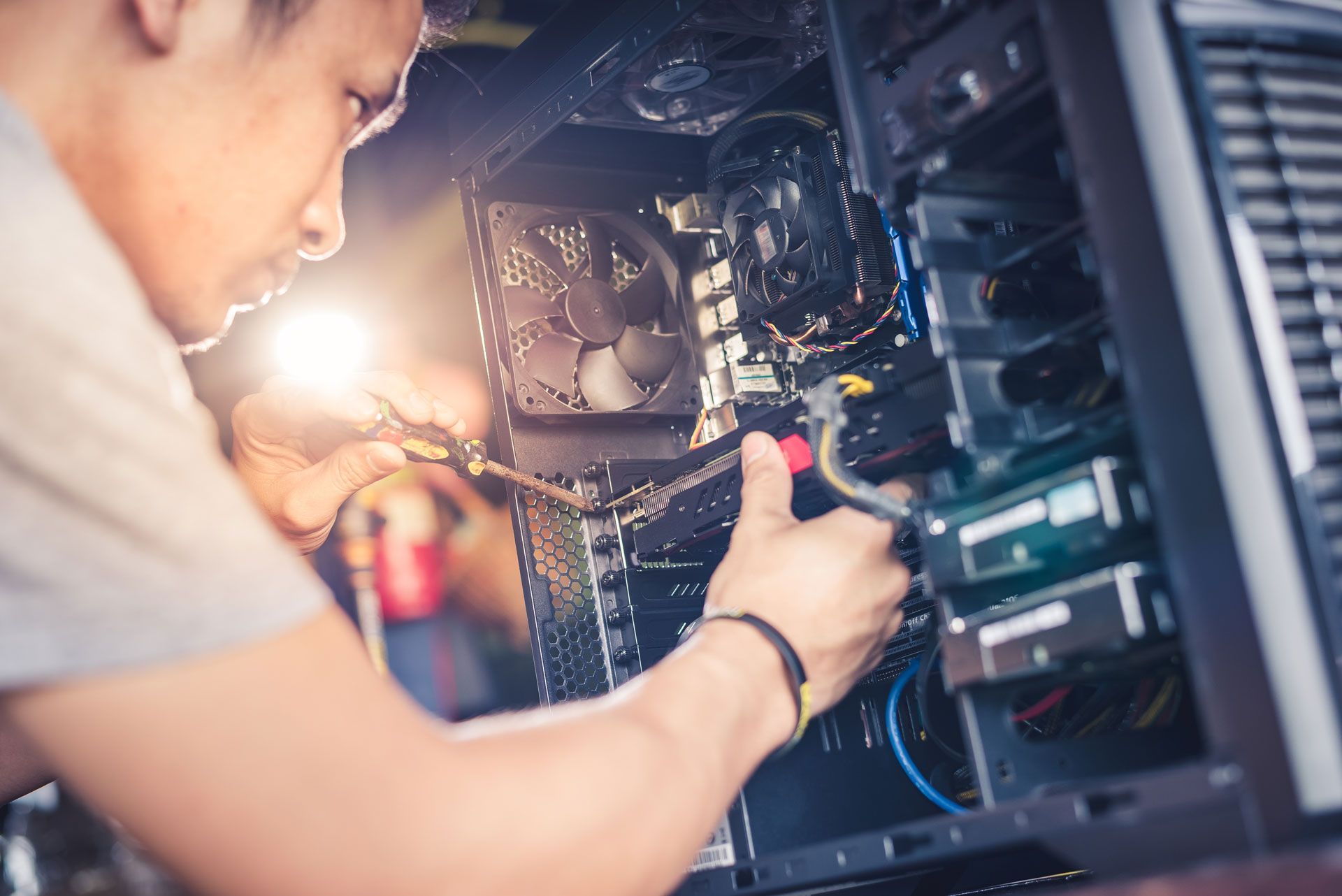 A person working on a computer tower with wires, likely repairing or upgrading components.