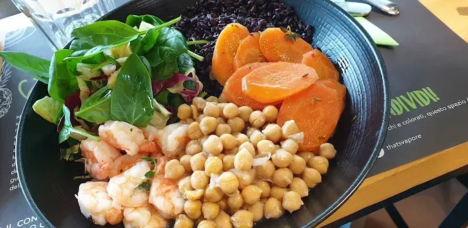 Una ciotola colorata con gamberi, ceci, carote, verdure e riso nero.