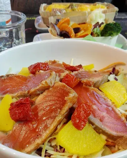 Insalata di salmone con pomodori secchi e verdure gialle, più contorni in un bar.