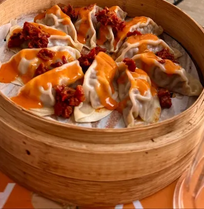 Ravioli al vapore cotti in una vaporiera di bambù, conditi con salsa e briciole.