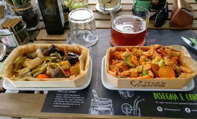 Due piatti di verdure in contenitori di legno su un tavolo, con un bicchiere di birra.