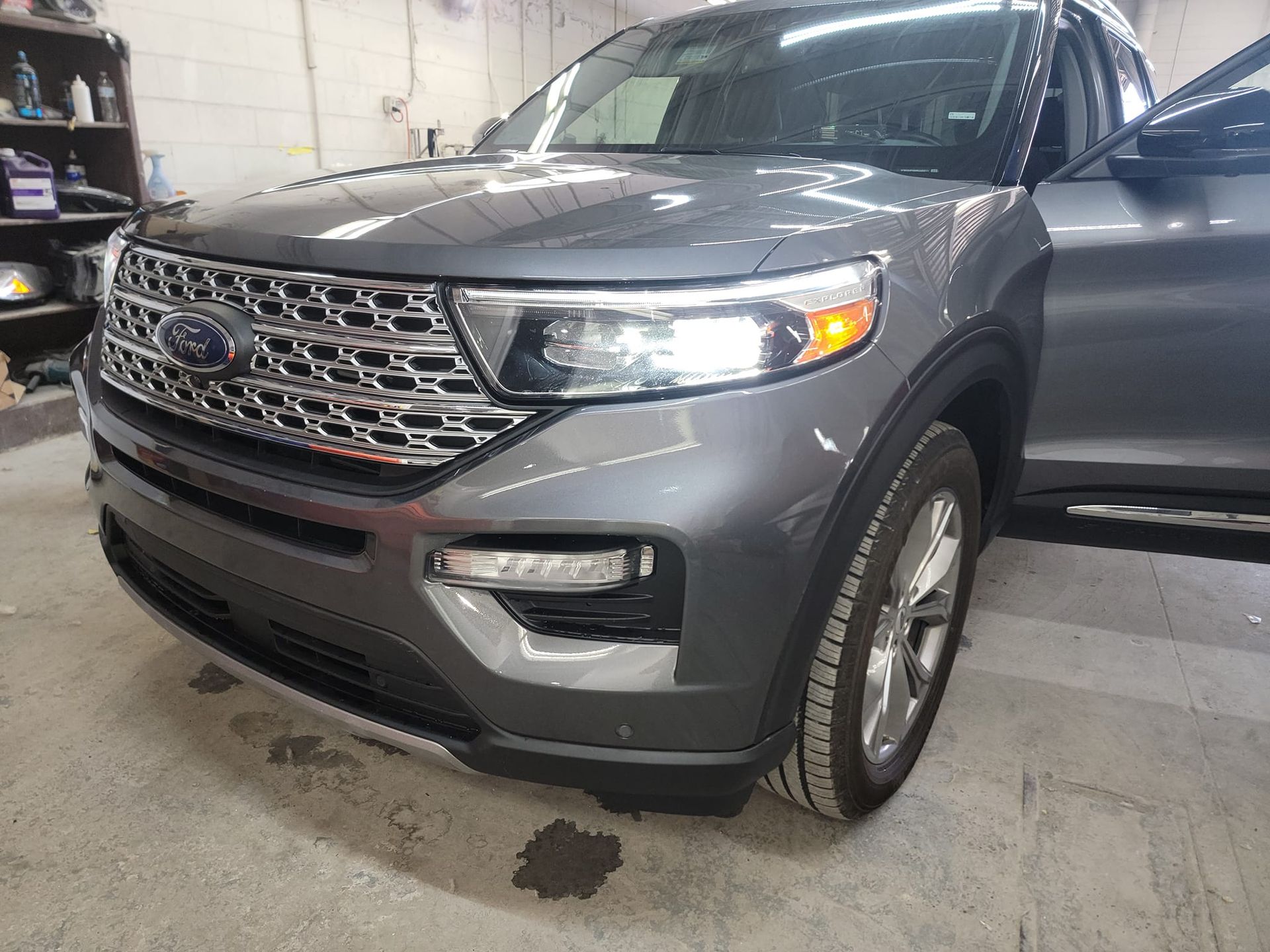 Gray Ford Explorer SUV parked inside a garage. The driver's side door is open.