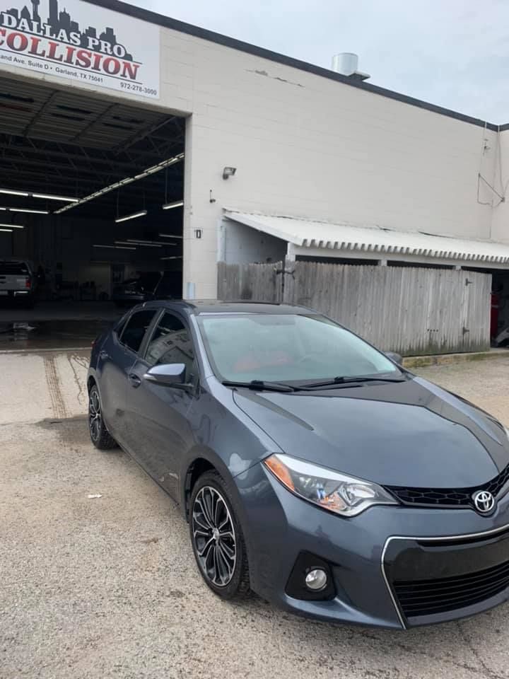 Gray Toyota Corolla parked outside Dallas Auto Collision shop.
