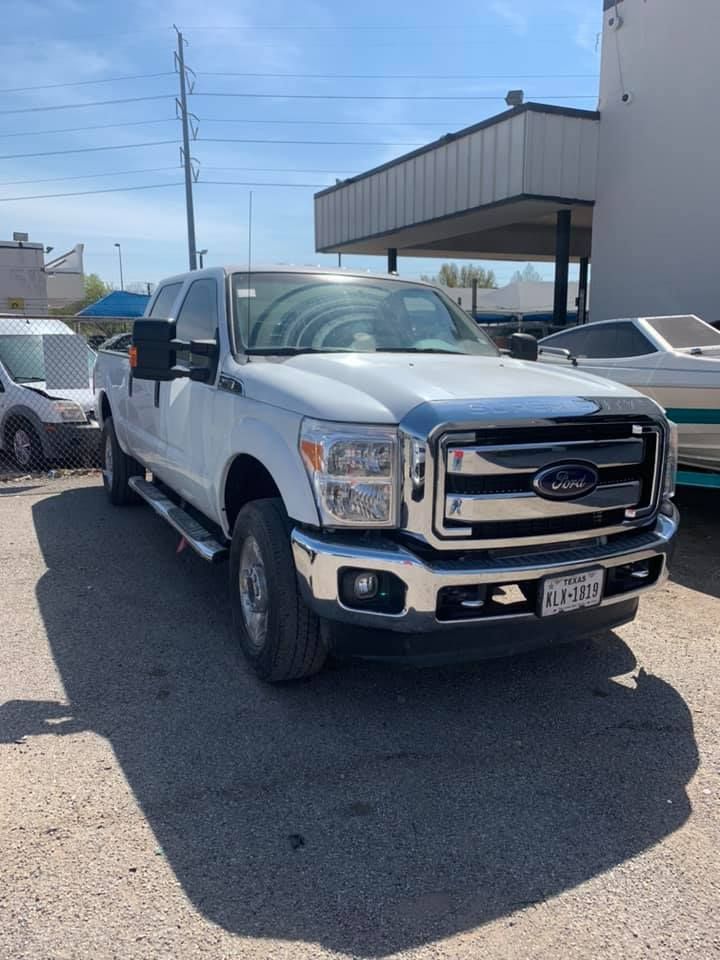 White Ford pickup truck parked outside on a sunny day; silver grill, chrome accents.