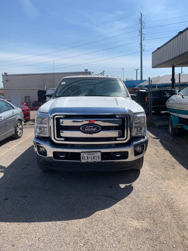 White Ford pickup truck parked outside on a sunny day; license plate visible.