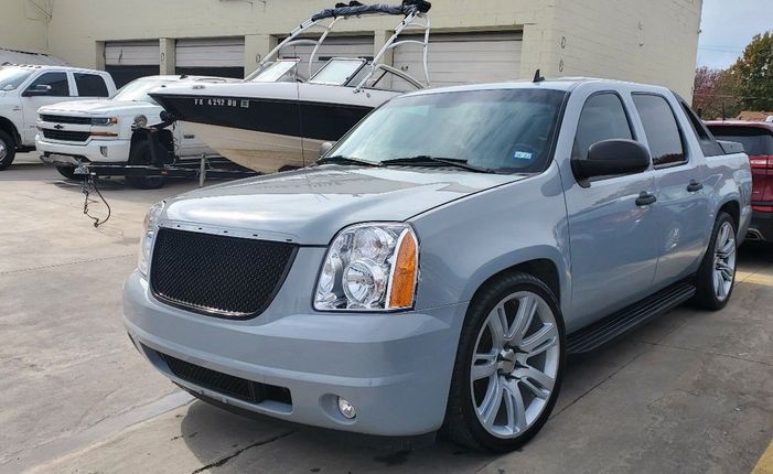 A white truck is parked in a parking lot next to a building.
