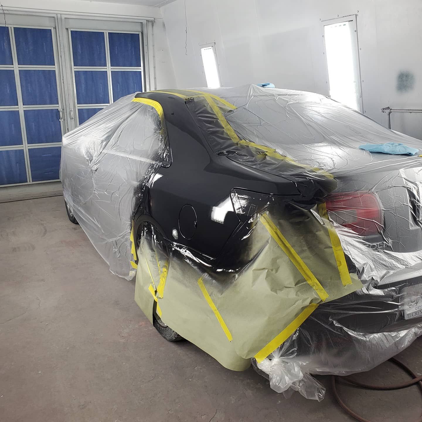 Person sprays red paint on a surface with a spray gun; background is paper-covered.