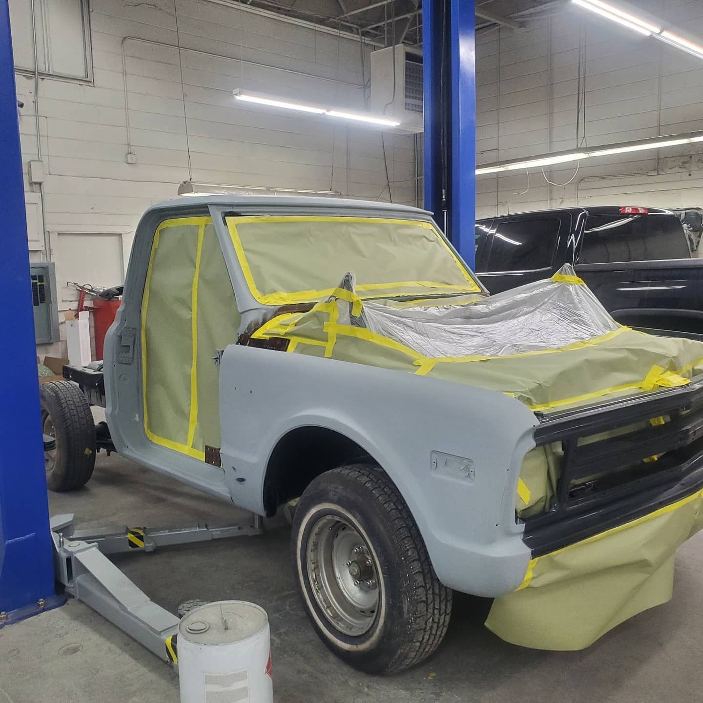 Gray classic Chevy truck in a shop, prepared for paint, masked.