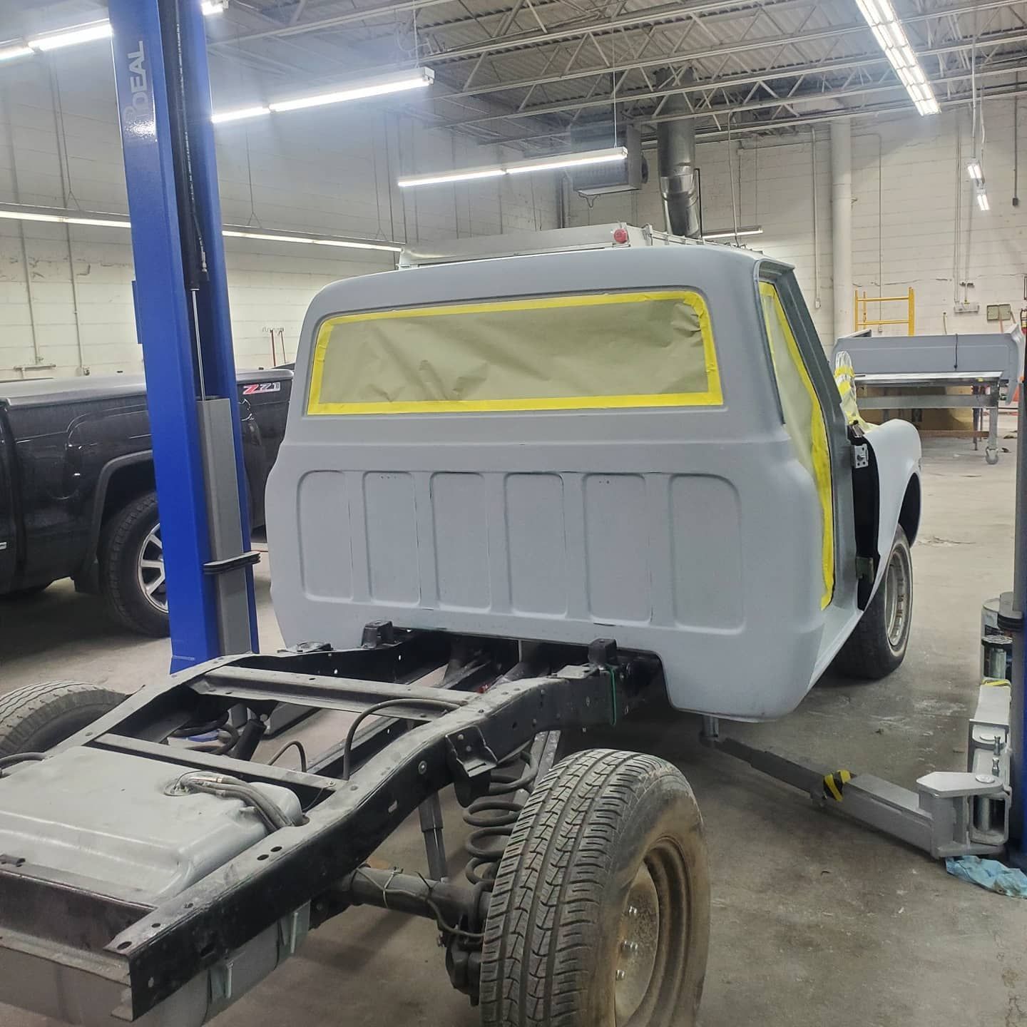 Classic truck cab on a chassis in a workshop, masked for painting.
