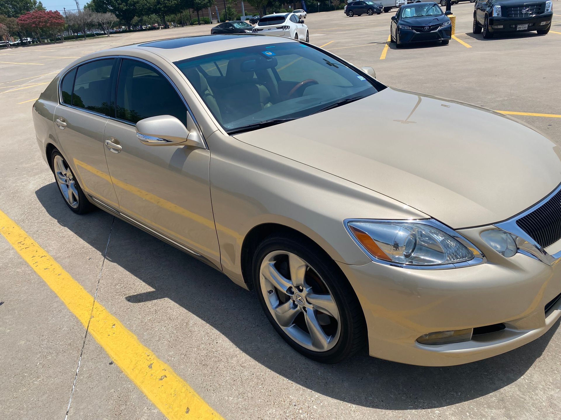 Gold Lexus sedan parked in a parking lot on a sunny day.