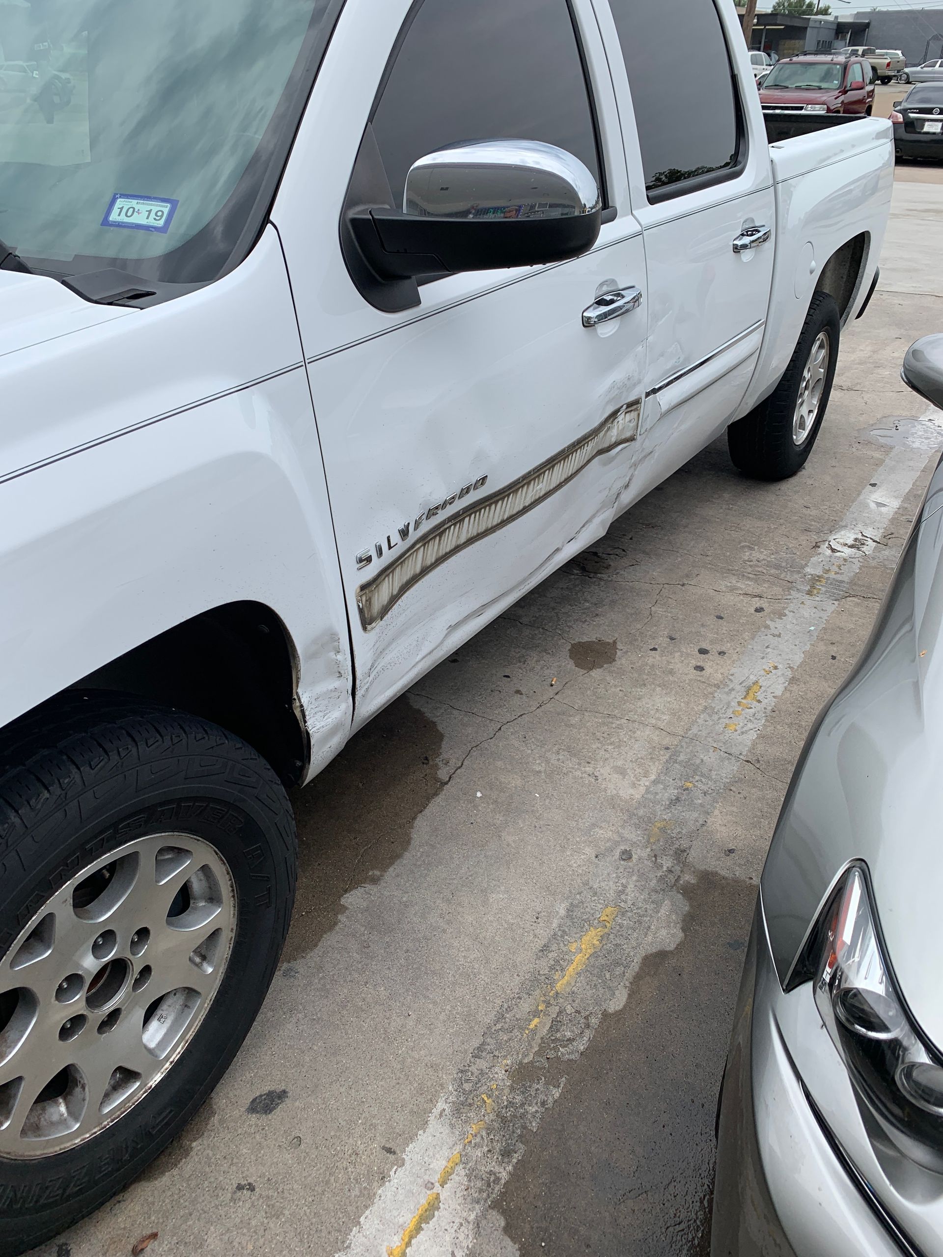 White pickup truck with significant damage on the side parked outside.