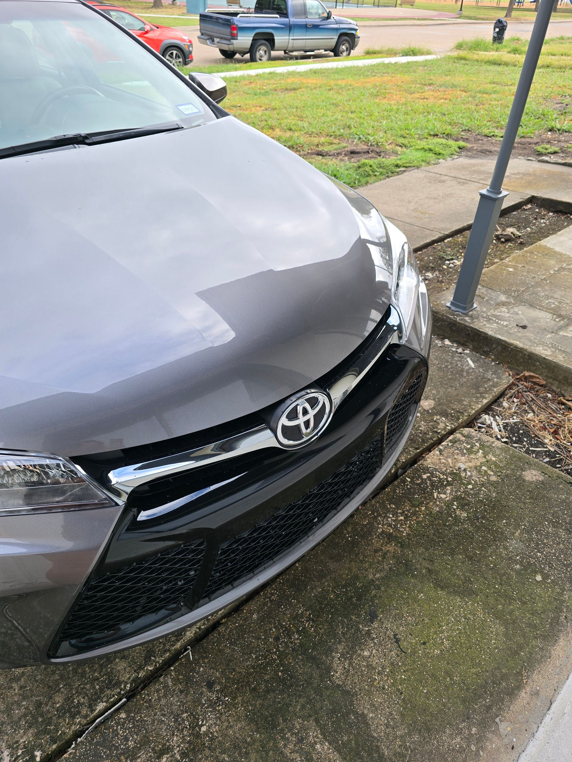 Gray Toyota car parked on a street, front view, with Toyota emblem on the grille.
