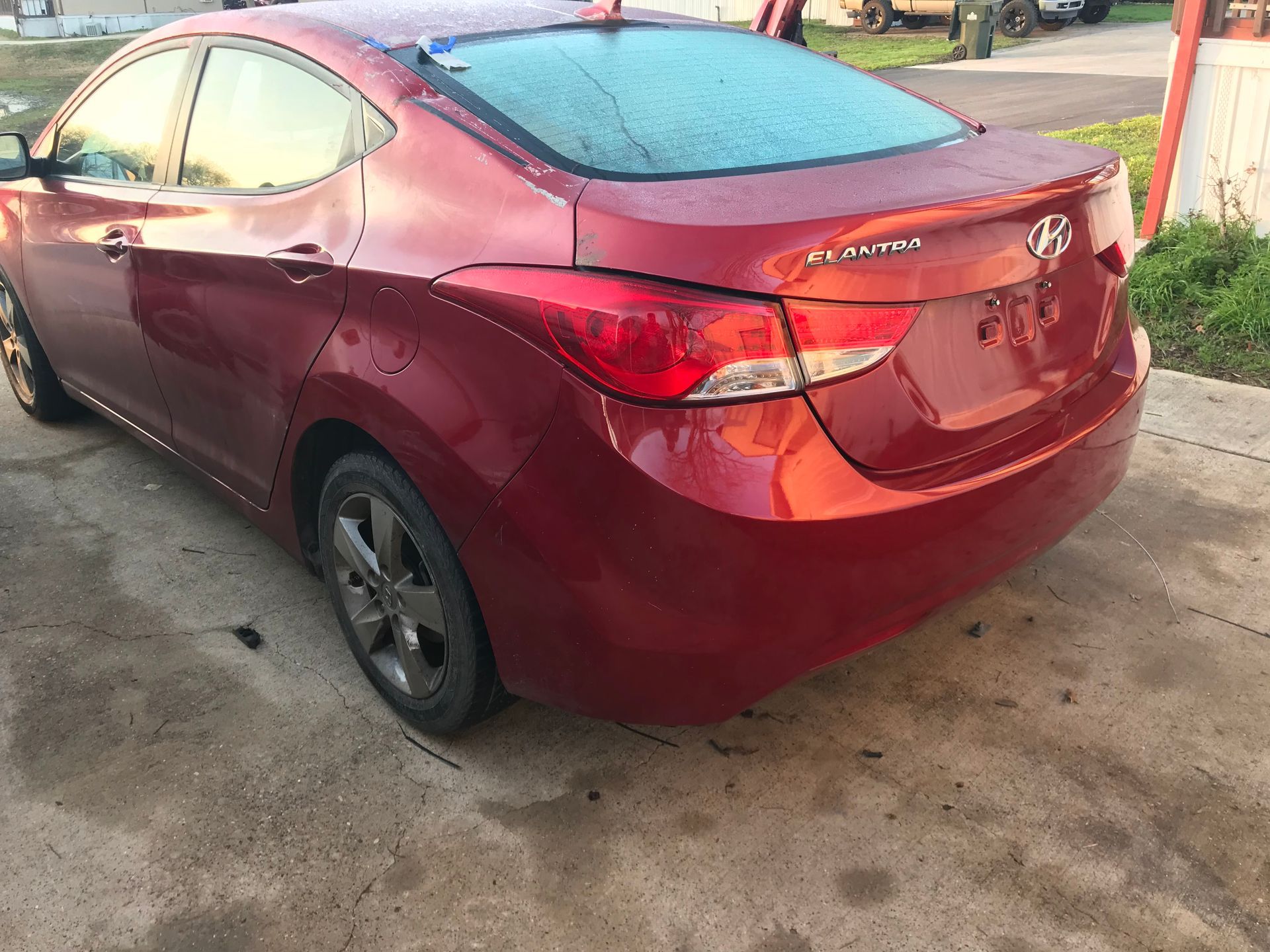 Red Hyundai Elantra sedan parked on a concrete driveway, rear view.