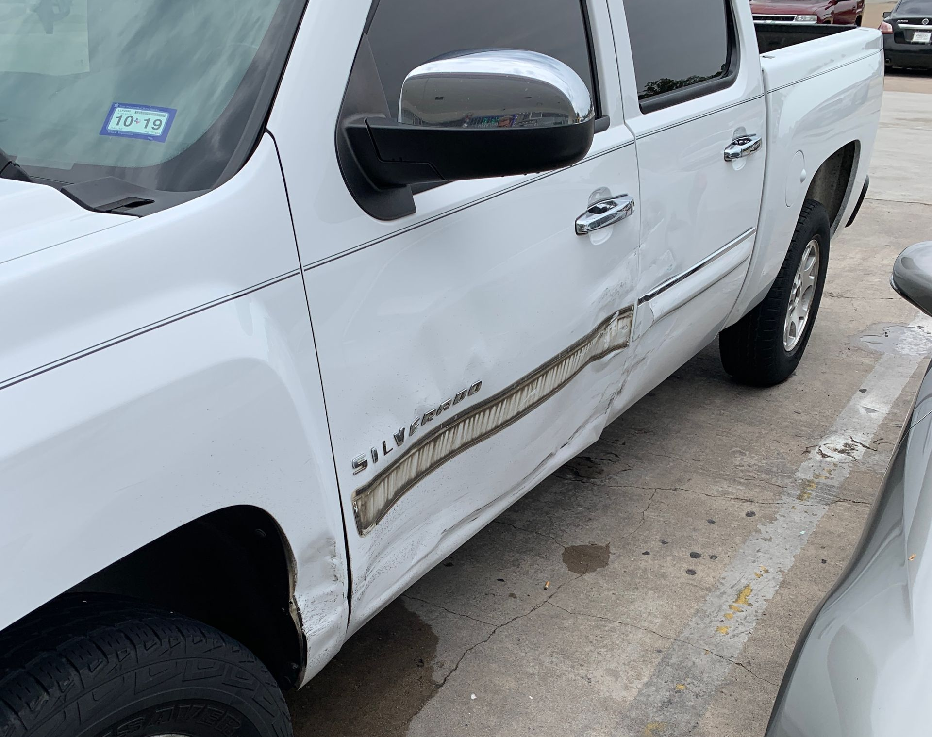 White Chevy Silverado truck with significant damage to the side panel.