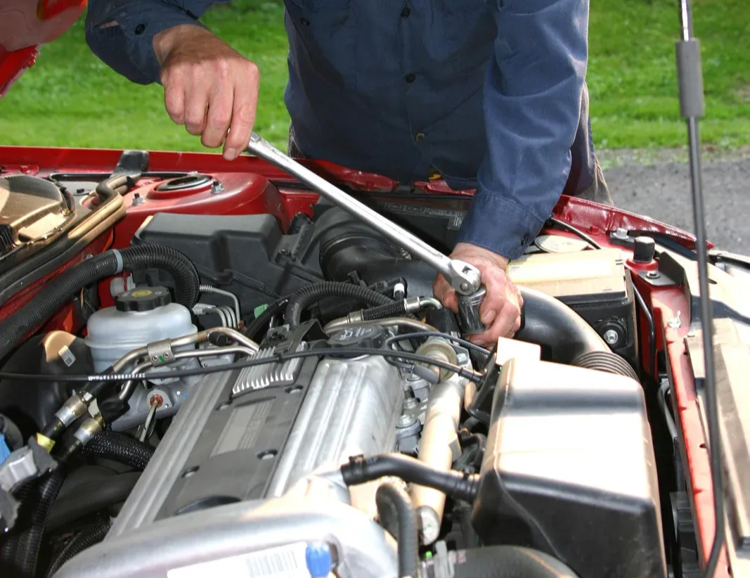 Mechanic working on a car engine, inspecting parts. Close-up of hands and engine components.