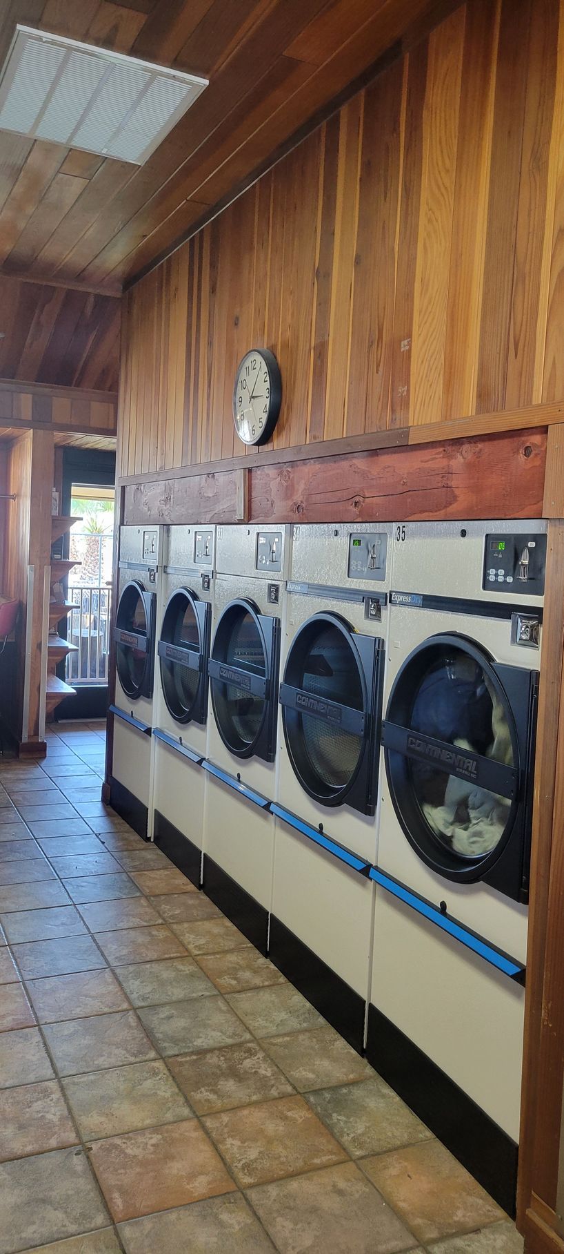 Row of washing machines in a laundromat, set against wood-paneled walls.