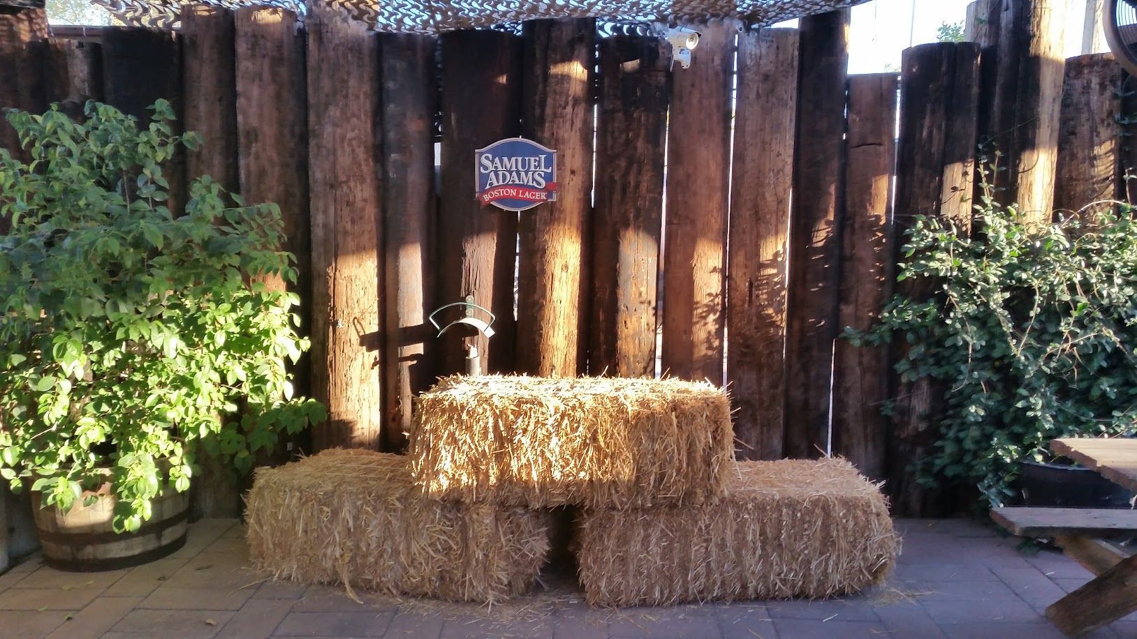 Hay bales form a stage, with a wooden backdrop, shrubs, and a sign.