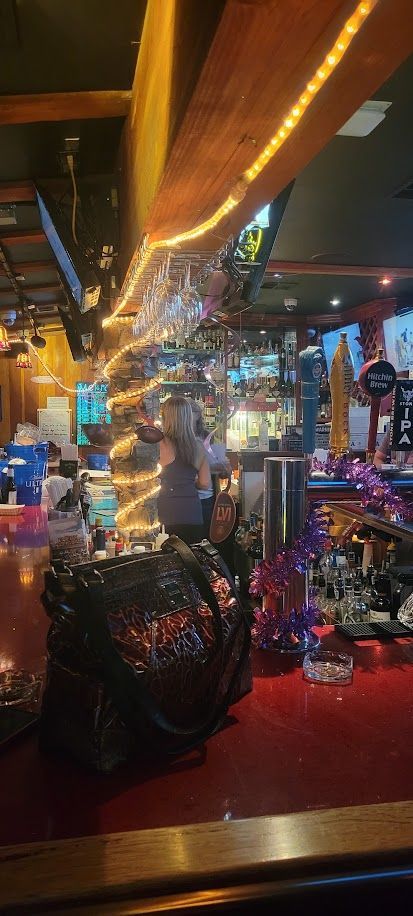 Bar interior with glowing lights, glasses, and a person behind the counter.