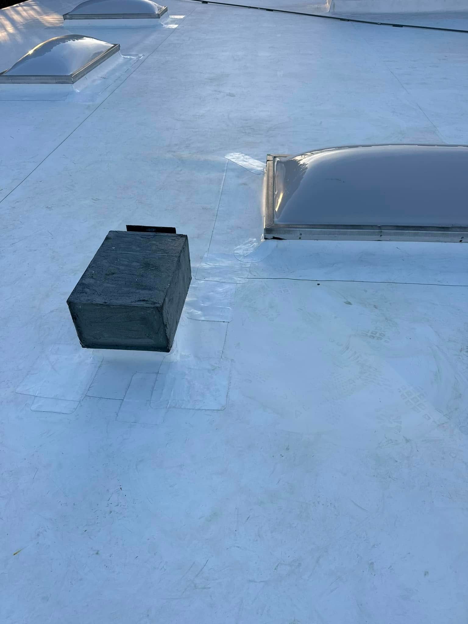 White roof with skylights and a rectangular structure, possibly a vent or chimney.