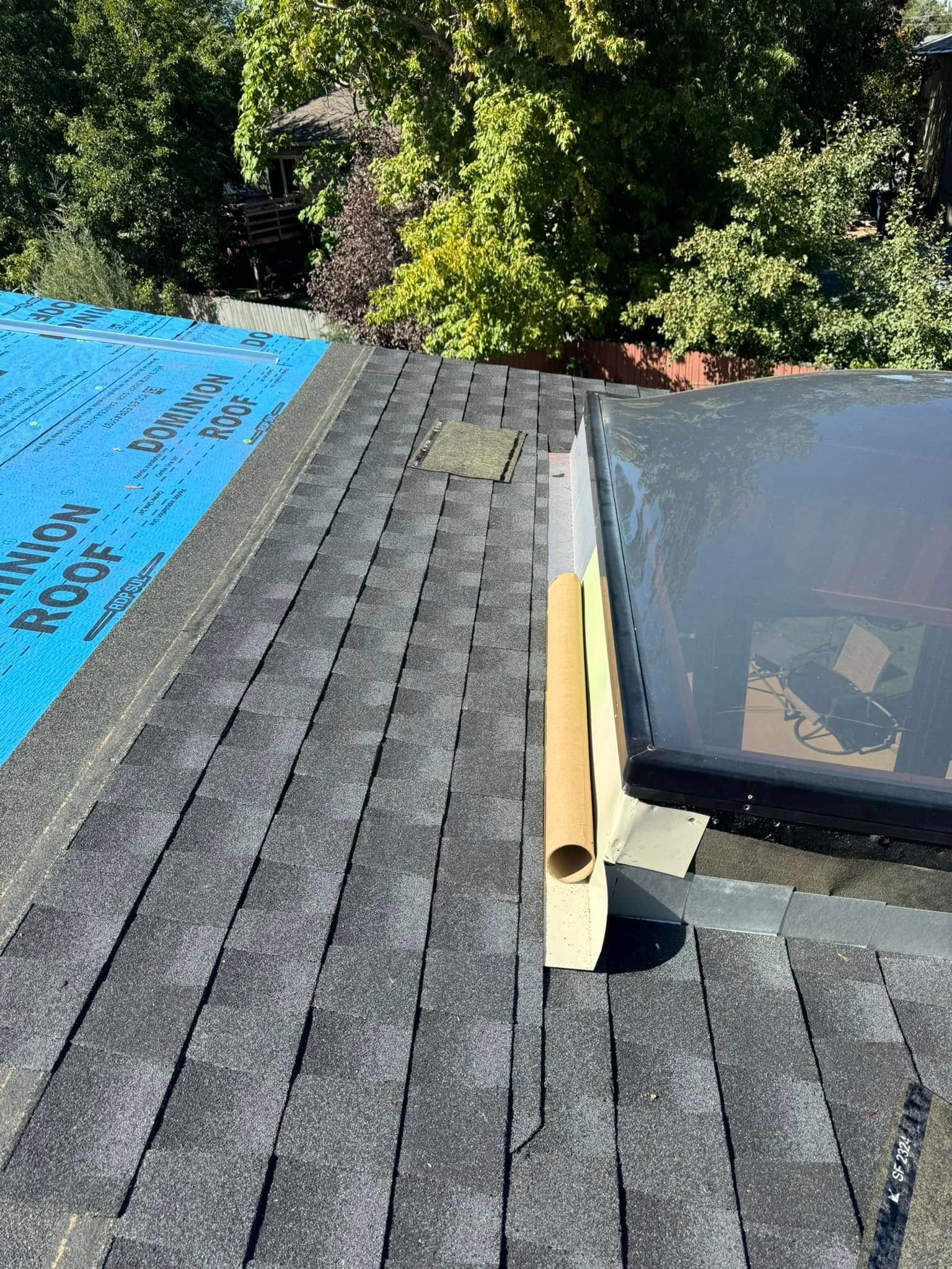 Roof with new shingles, a skylight, and blue underlayment.