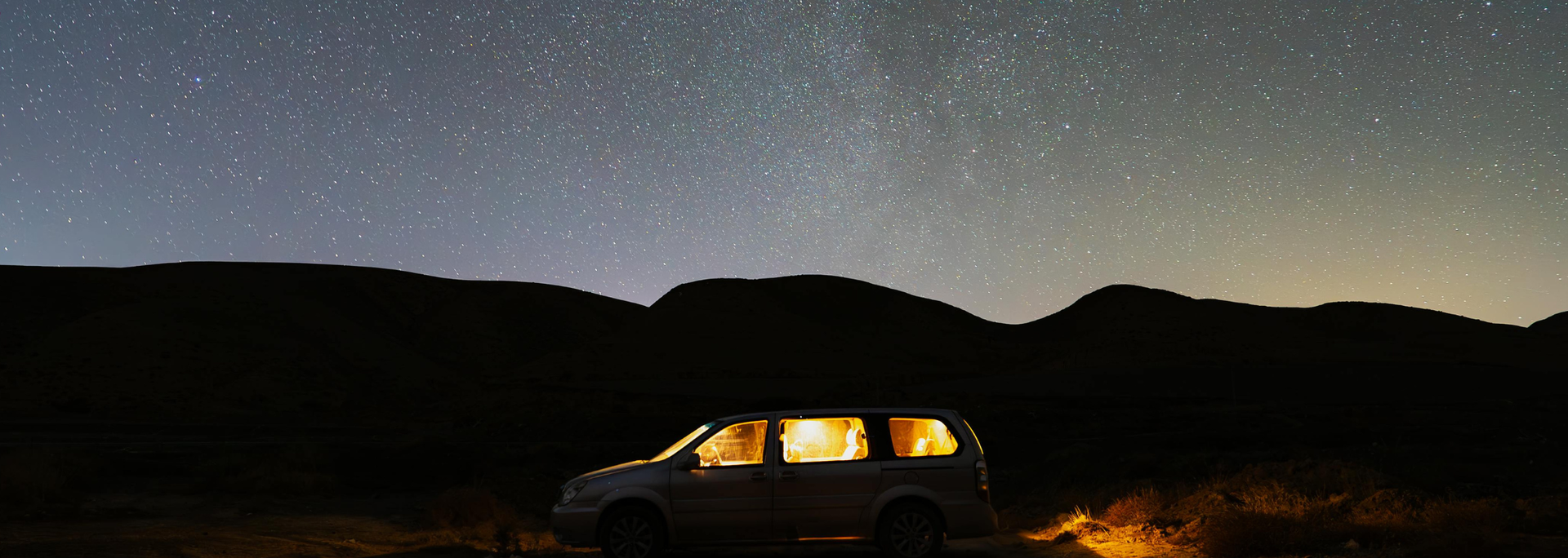 Picture of a car under the stars of the night sky. 