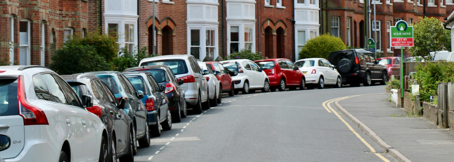 Picture of a row of cars parked on a residential street.