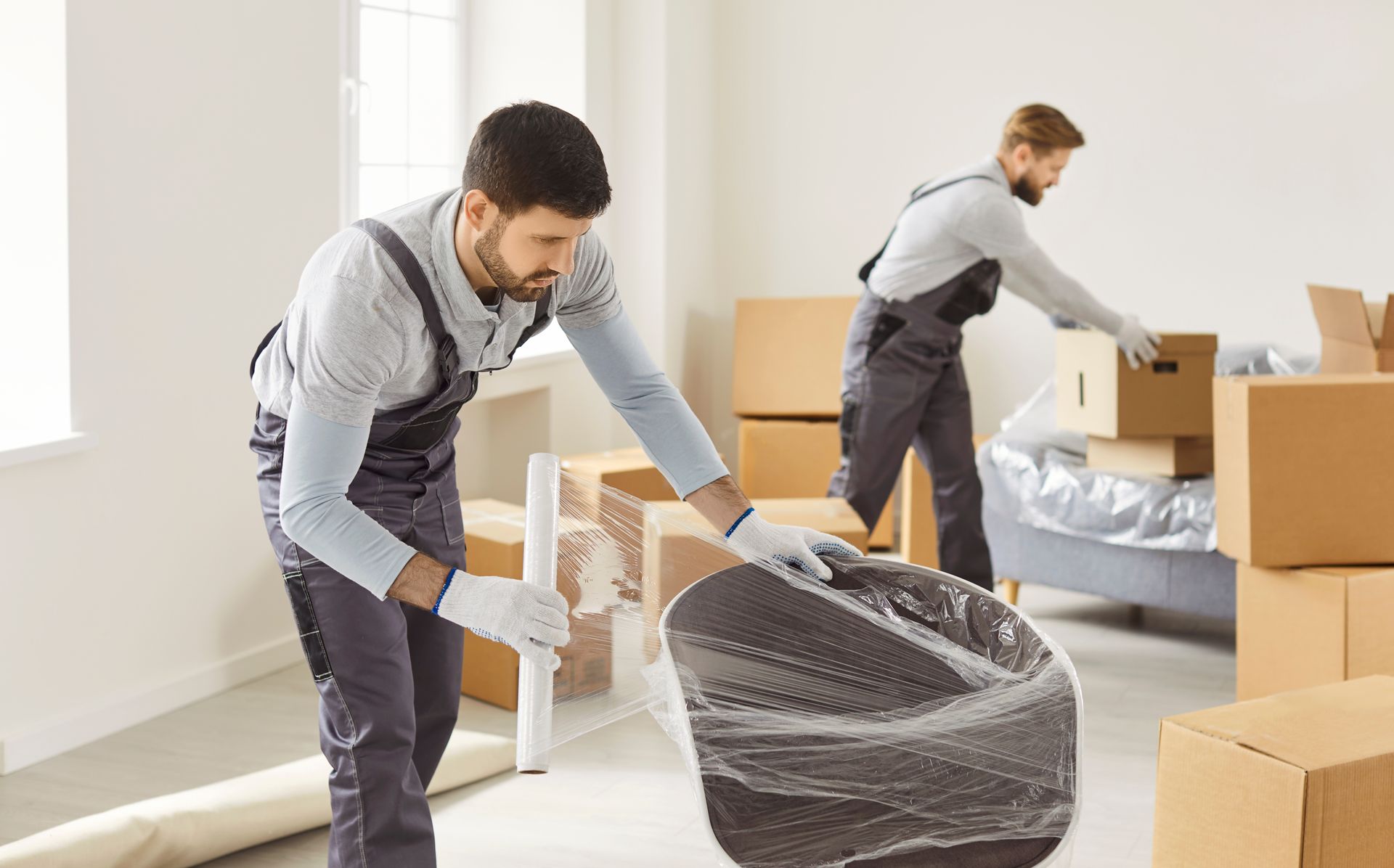 Two professional movers in uniform pack furniture.