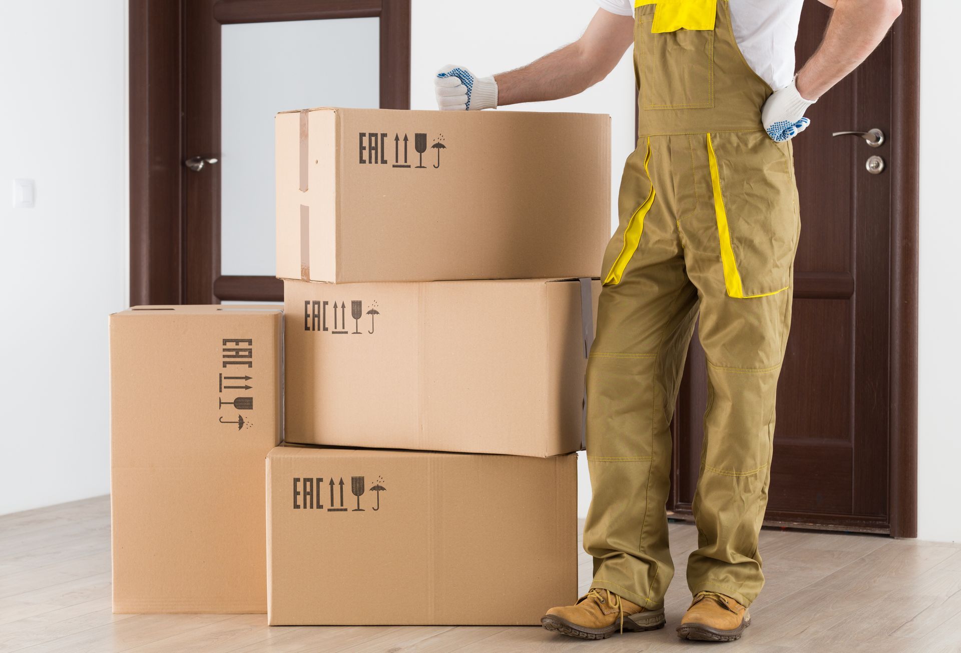 A storage mover stands next to a tower of boxes in front of an apartment.