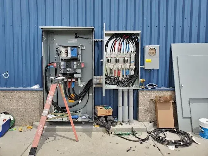 A large electrical box is being installed on the side of a building.