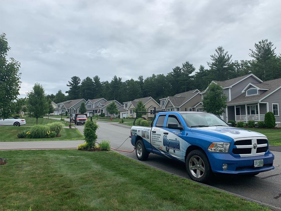 A blue pickup truck parked on a residential street in a suburban neighborhood under a cloudy sky.