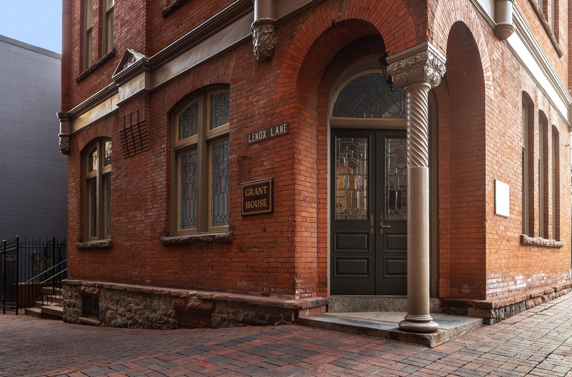 A large brick building with a black door and a pillar in front of it.