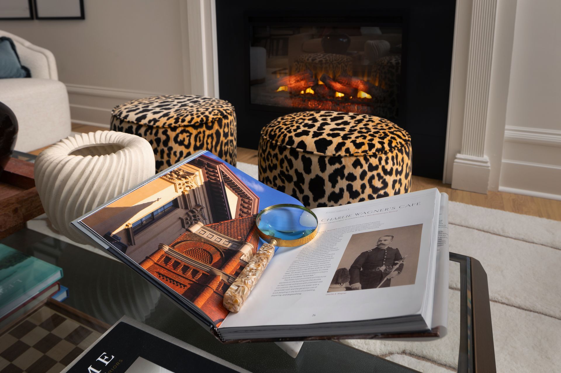 A living room with a fireplace , ottomans and a book on a table.