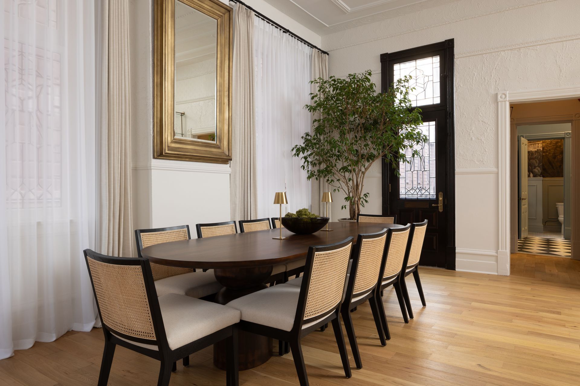 A dining room with a table and chairs and a mirror.