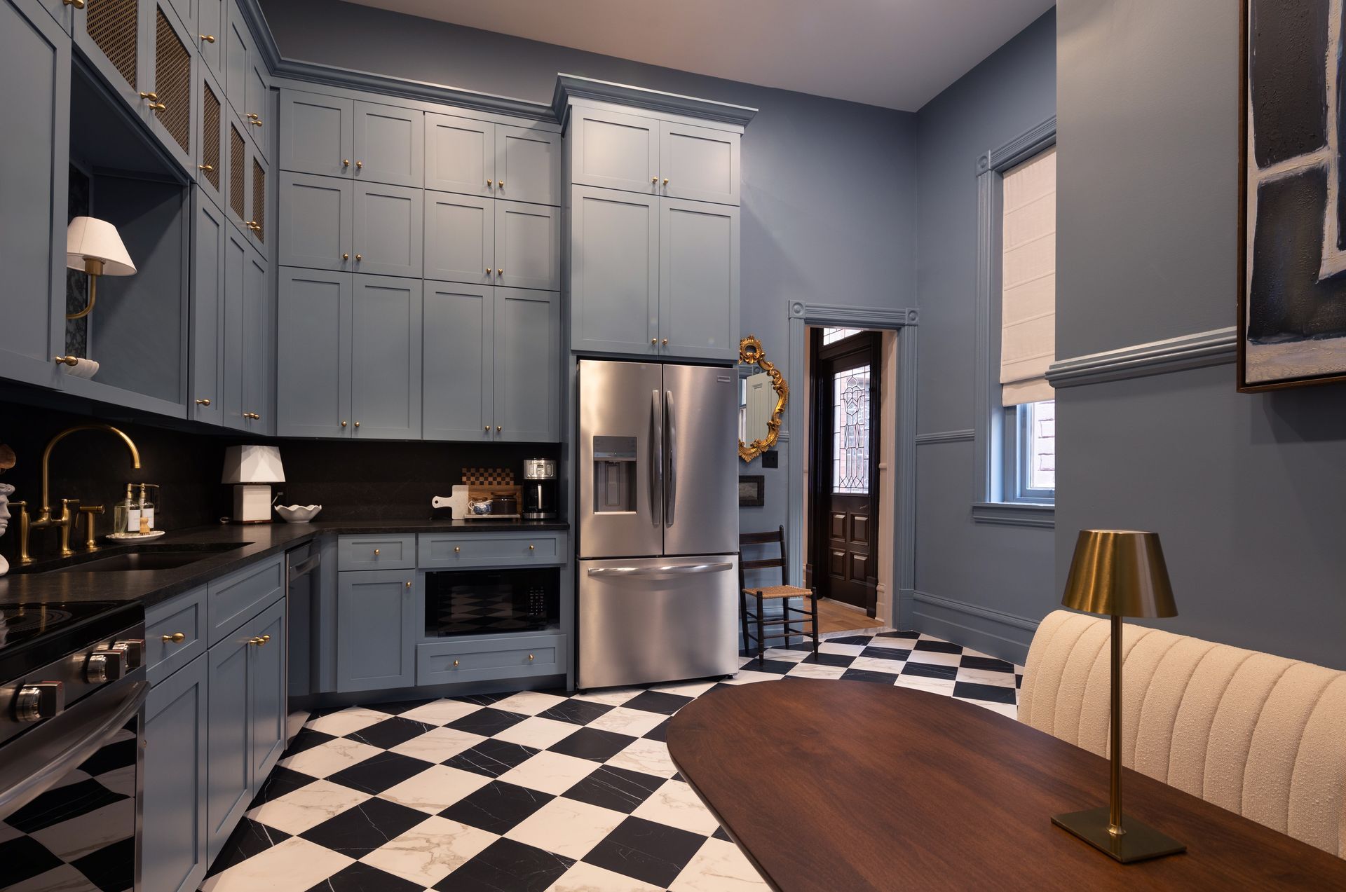 A kitchen with blue cabinets and a black and white checkered floor.