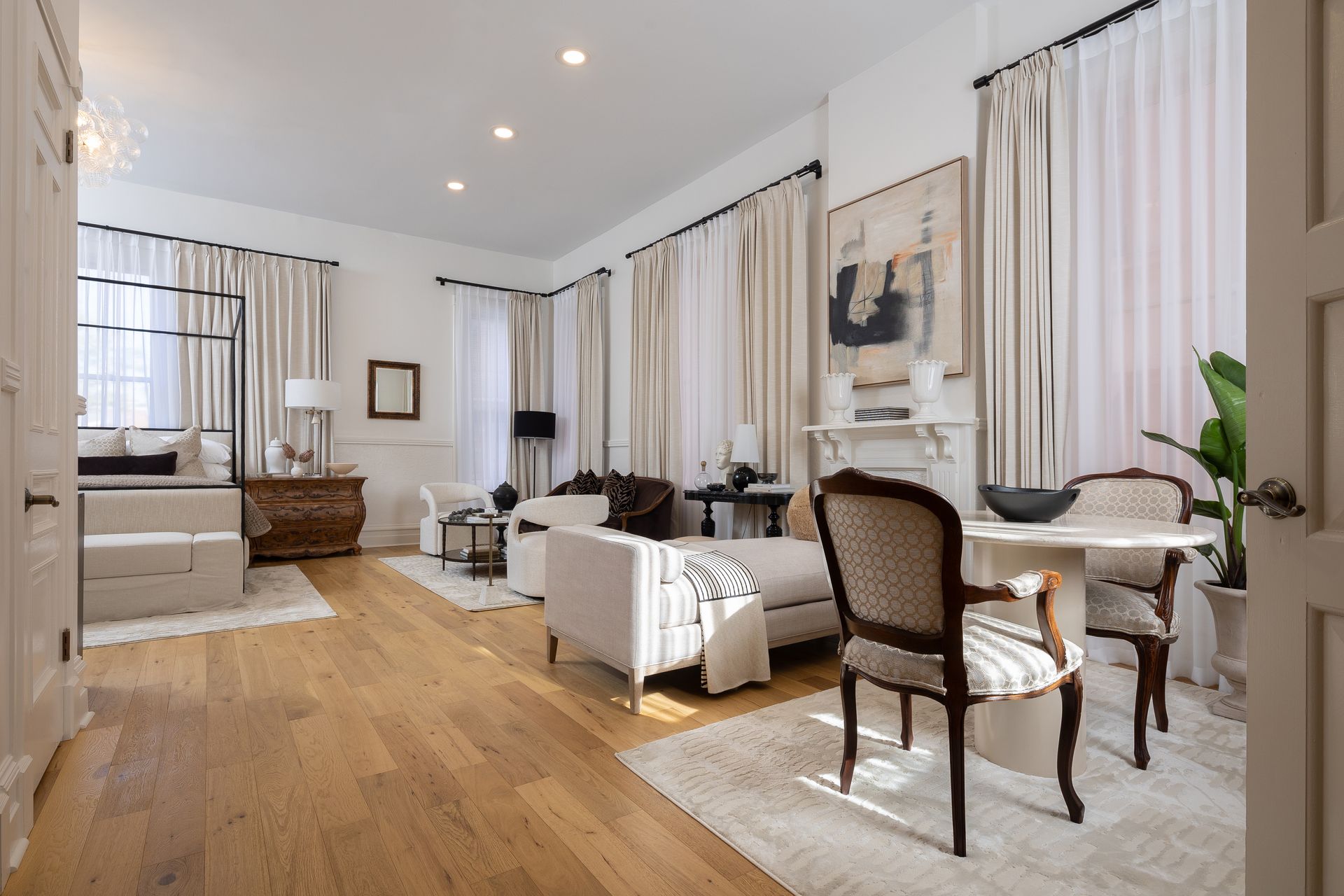 A living room with a couch , chairs , a table and curtains.