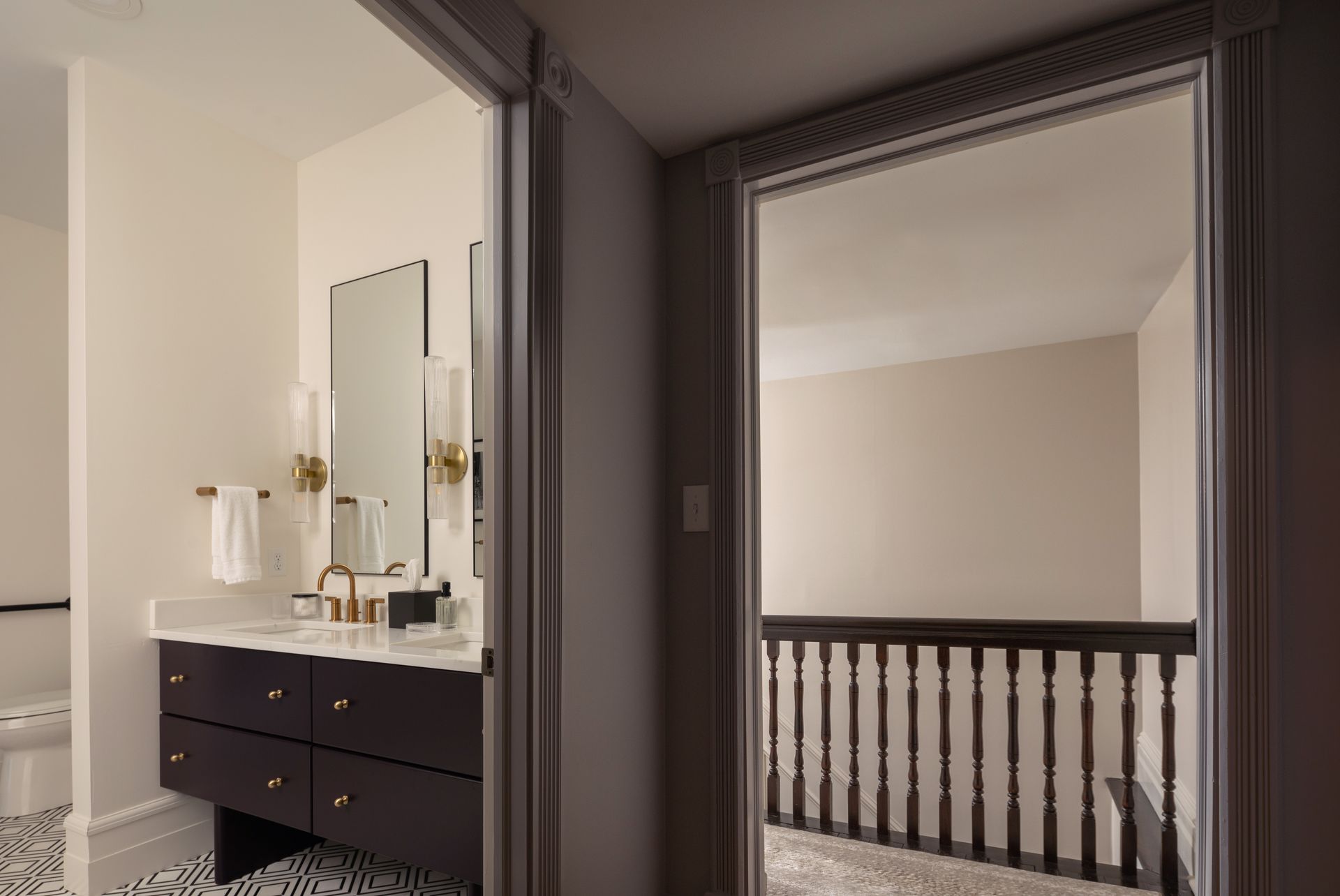 A bathroom with a sink , mirror and stairs leading to a bedroom.