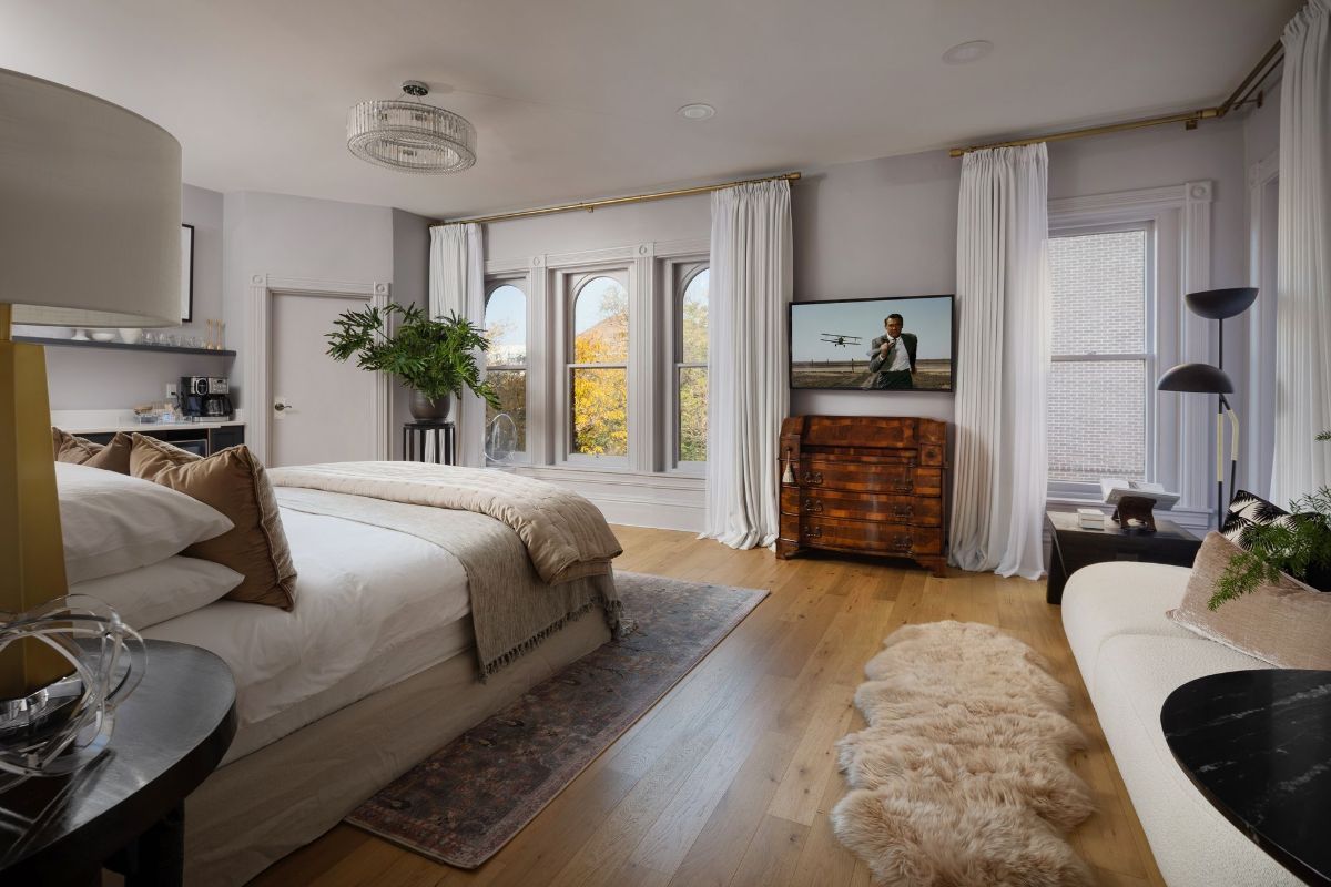 A bedroom with a large bed , a couch , a television and a rug.