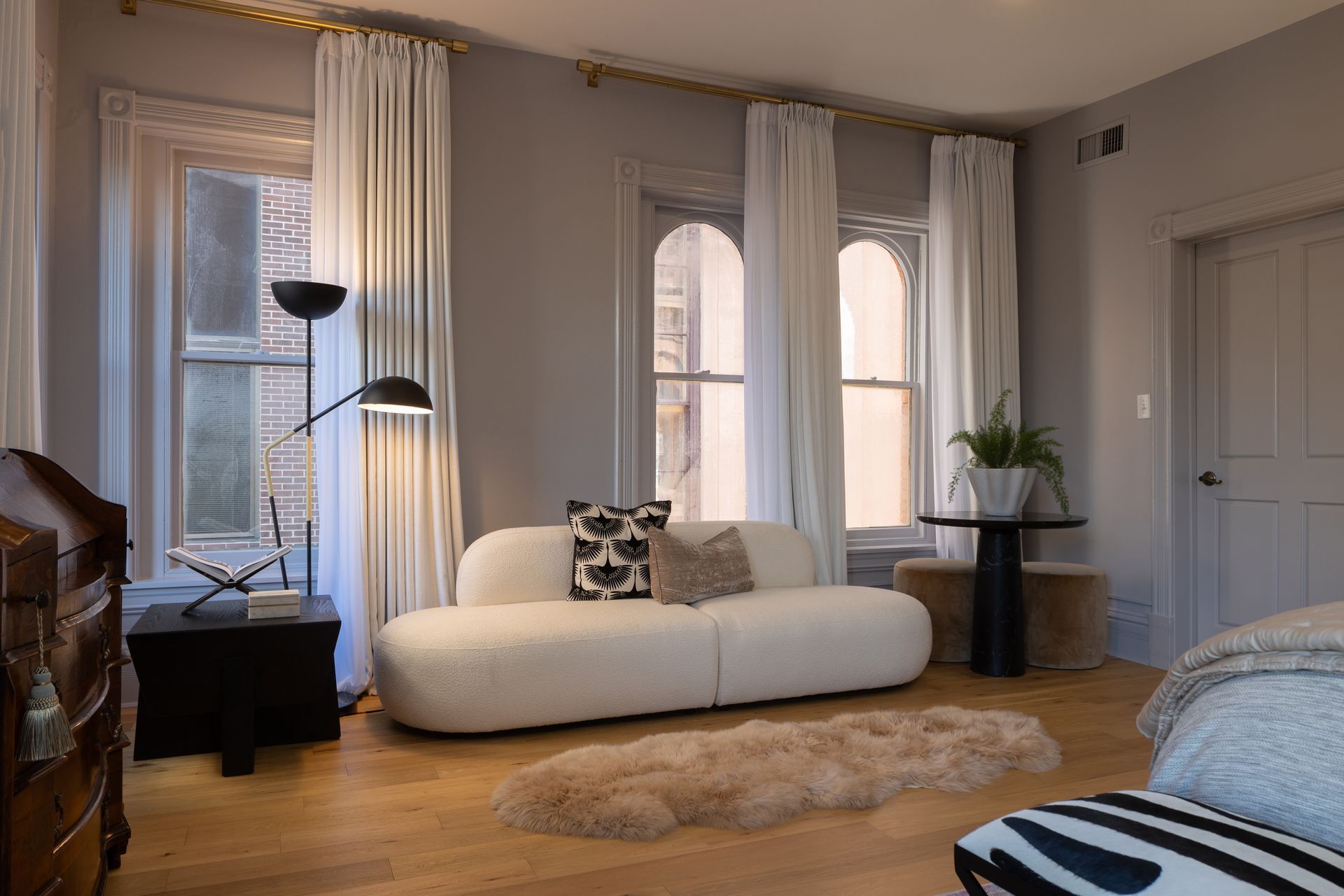 A living room with a white couch and a rug on the floor.