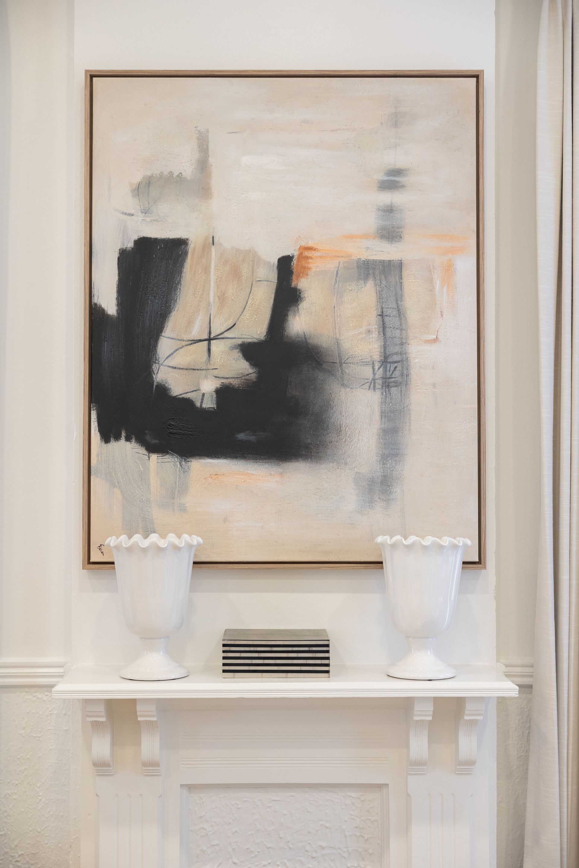 A large painting is hanging on a wall above a fireplace.