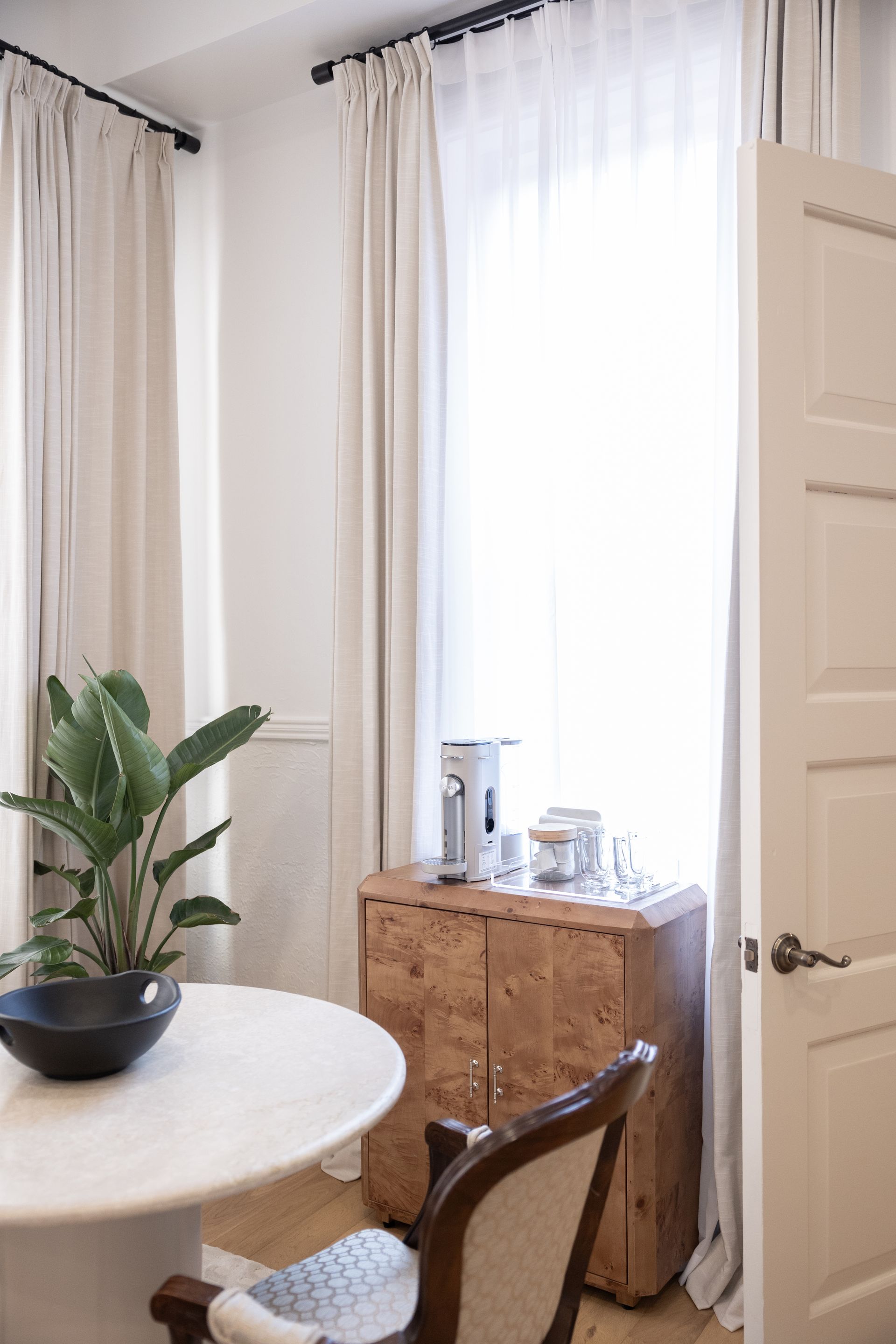 A room with a table , chair , plant and window.