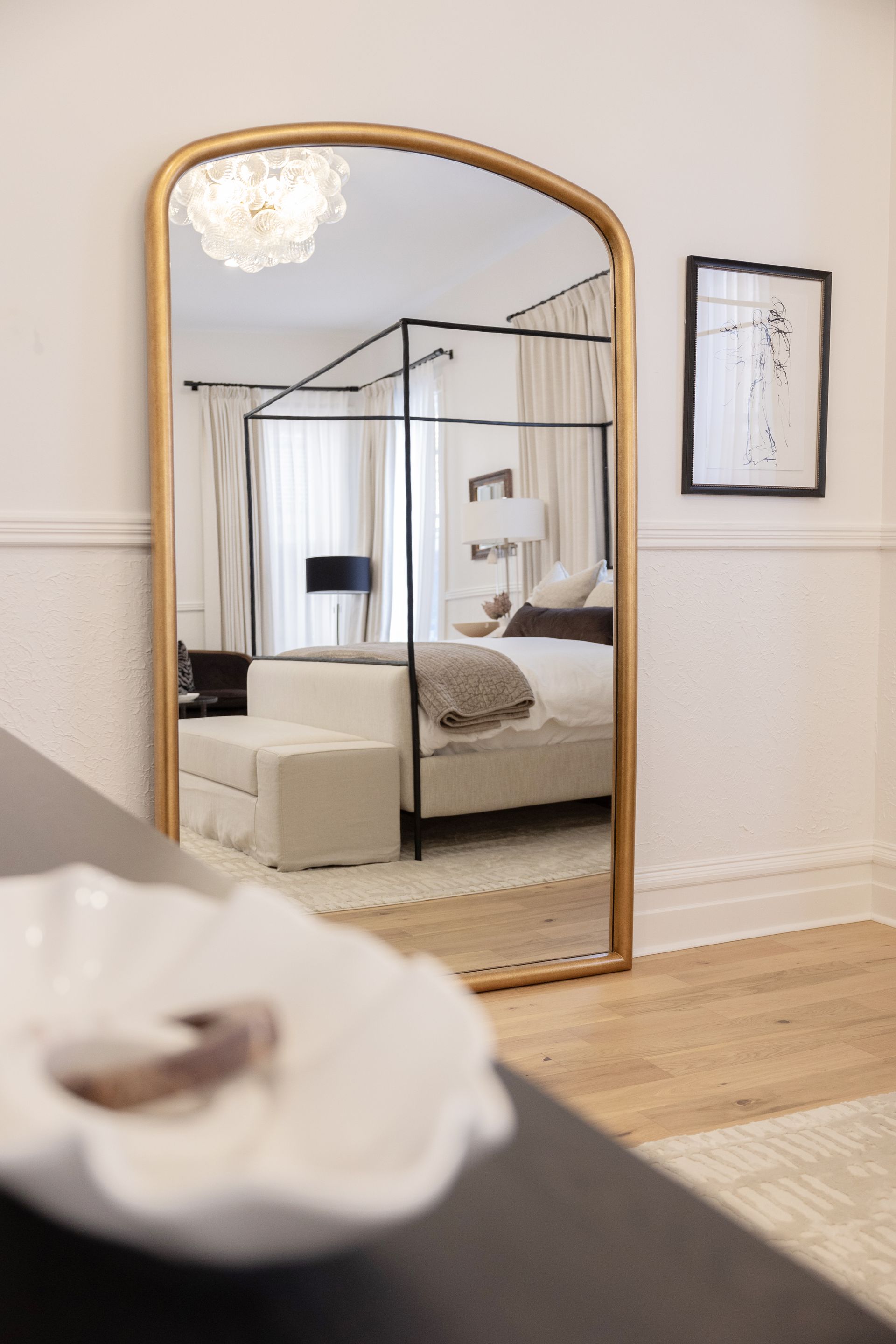 A bedroom with a canopy bed and a large mirror.