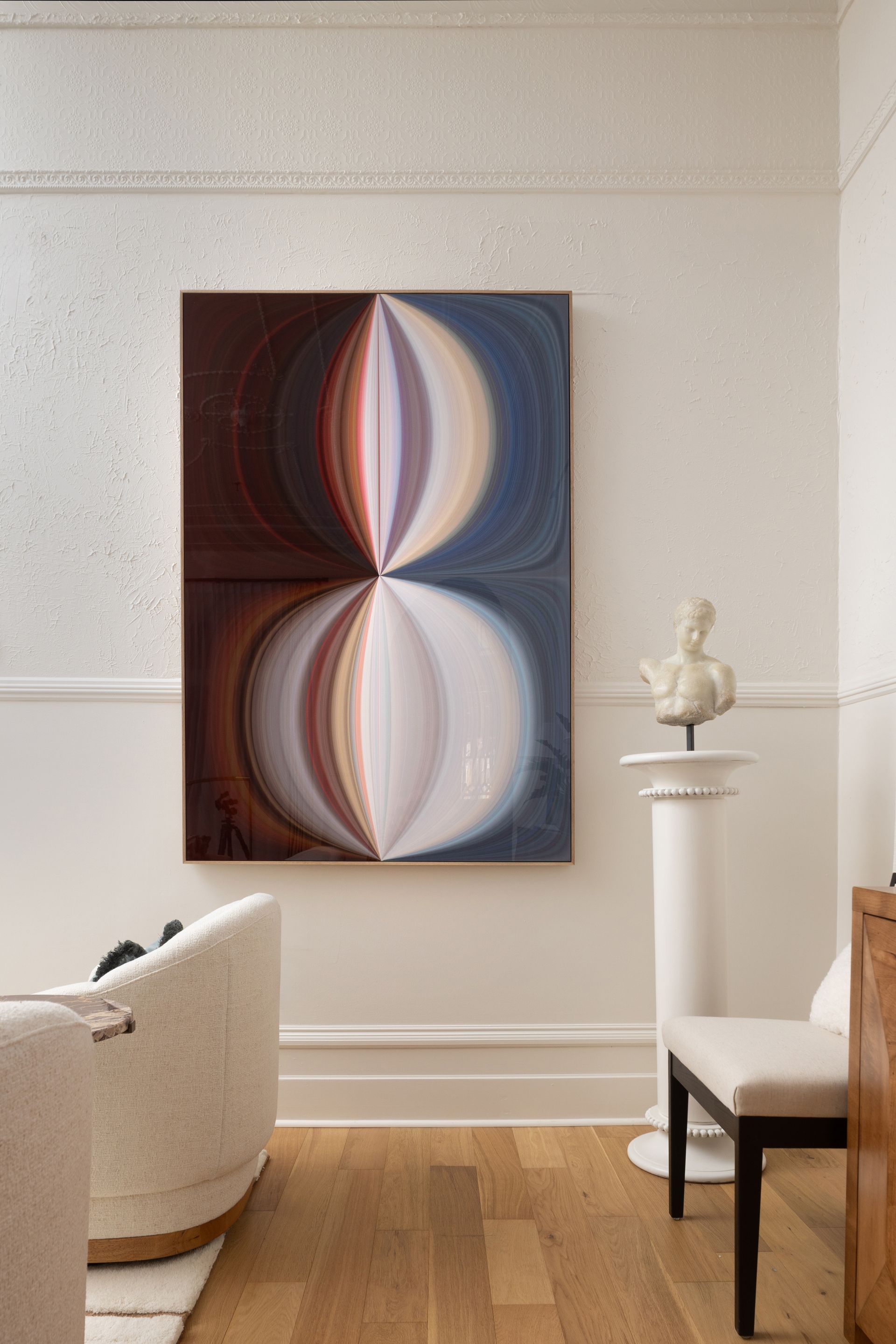 A living room with a couch , chair , and a painting on the wall.