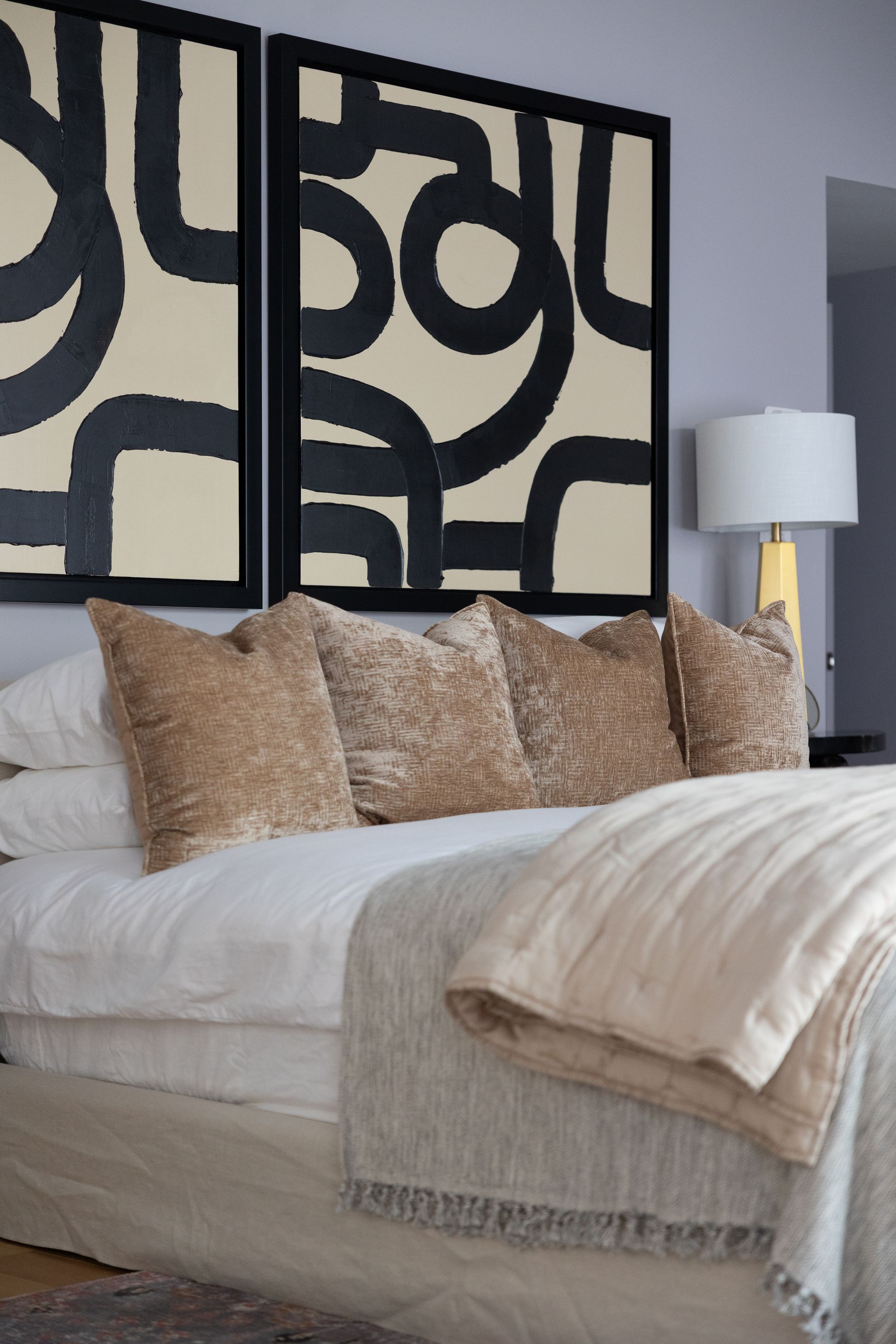 A bedroom with a bed and two paintings above it