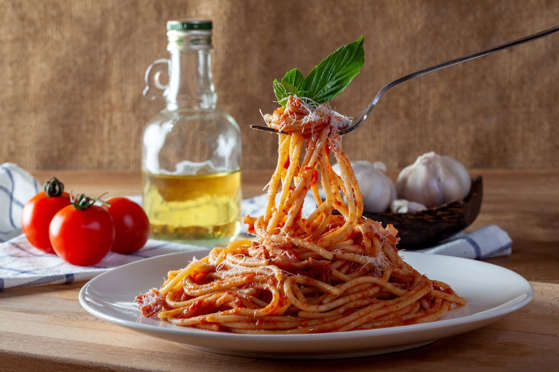 A plate of spaghetti with tomato sauce is being eaten with a fork.