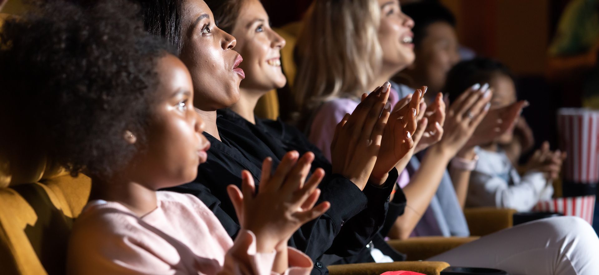 A group of people are sitting in a theater clapping their hands.
