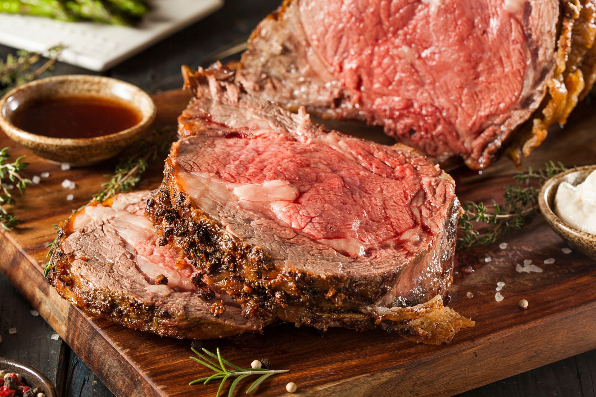 A large piece of roast beef is sitting on a wooden cutting board.