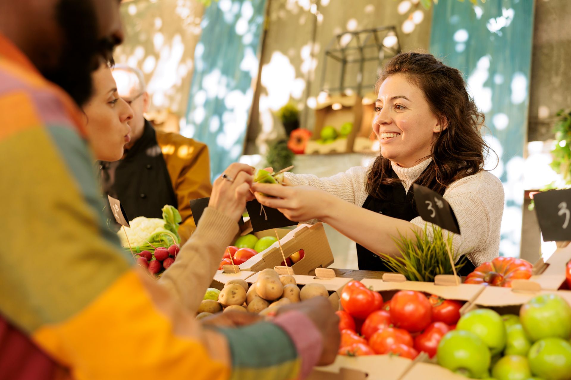 A woman is selling apples to a man at a farmers market.