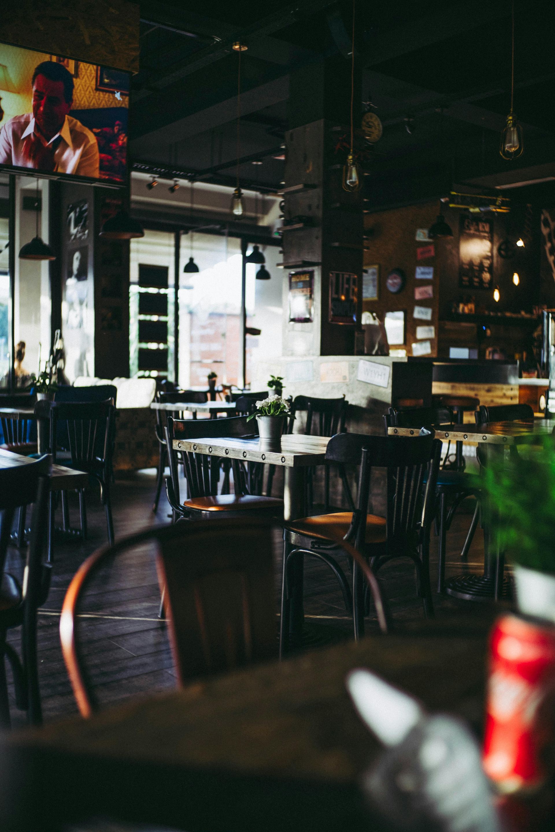 A restaurant with tables and chairs and a television on the wall.