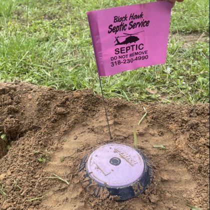 Pink flag marking septic tank lid. Flag reads 